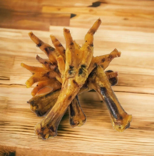 Dried chicken feet arranged on a wooden surface.