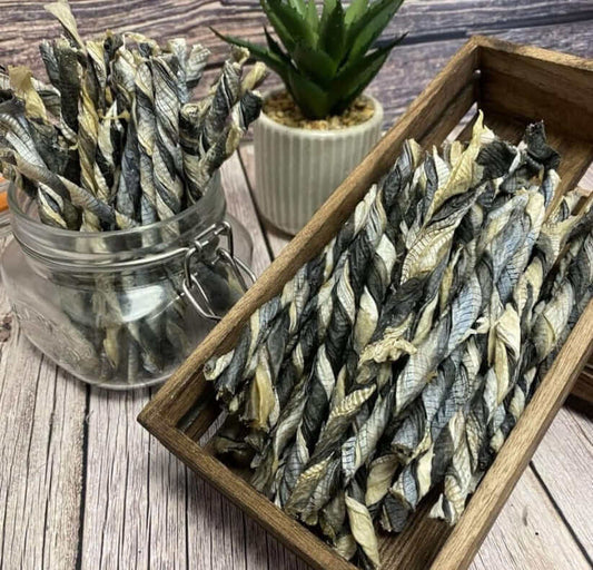 Crunchy fish skin dog treats in wooden box and glass jar on rustic wooden surface with succulent plant in the background.